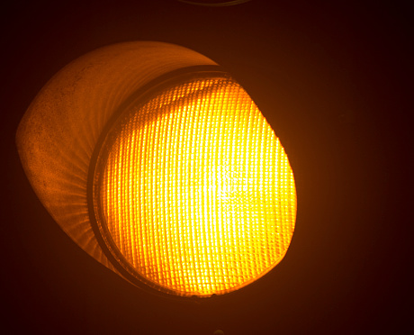 Orange amber traffic light photo at night on black background.
