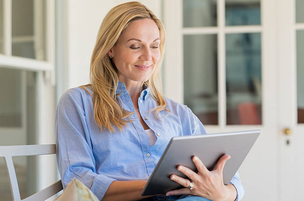 femme à l'aide d'une tablette - digital tablet women enjoyment happiness photos et images de collection