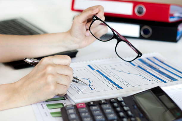 Businesswoman analyzing graphic and using calculator in the office