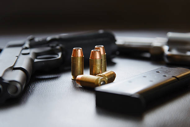 .45 Caliber hollow point bullets near handgun and magazine .45 Caliber hollow point bullets near handgun and magazine on leather furniture forty five caliber handgun stock pictures, royalty-free photos & images