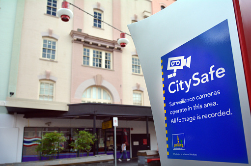 Brisbane, Australia - September 25, 2014: Woman walks past a CitySafe sign in Brisbane. City Safe Closed Circuit Television cameras are monitored 24 hours a day and help to deter crime or terror activity in public spaces in Brisbane.