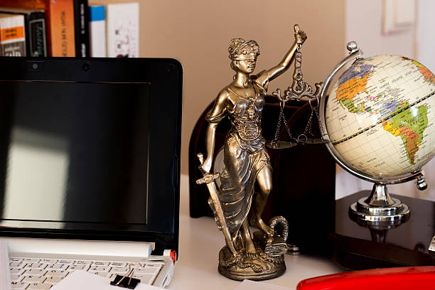 Law and business concept, statue, world map and laptop stock photo