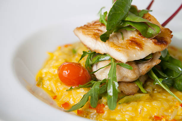 Fish fillet with risotto Fried white fish fillet with yellow risotto hake stock pictures, royalty-free photos & images