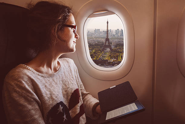 mulher com e-livro no avião de viagem para paris - airplane window indoors looking through window - fotografias e filmes do acervo
