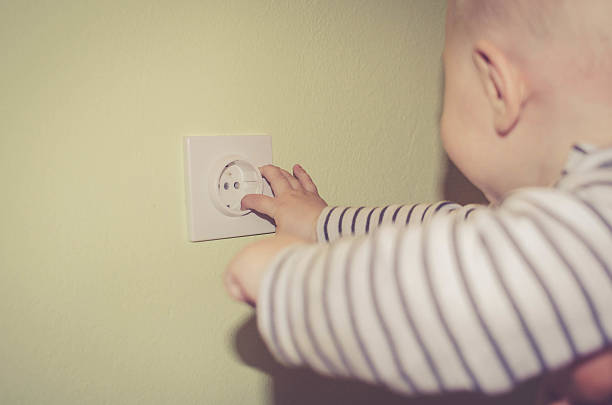 istock Dangerous baby sticking fingers into electrical outlet 531424732