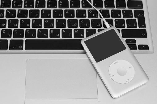 Pavlograd, Ukraine - December 13, 2014: iPod classic 160 Gb with airpods on silver metal laptop. Studio shot.