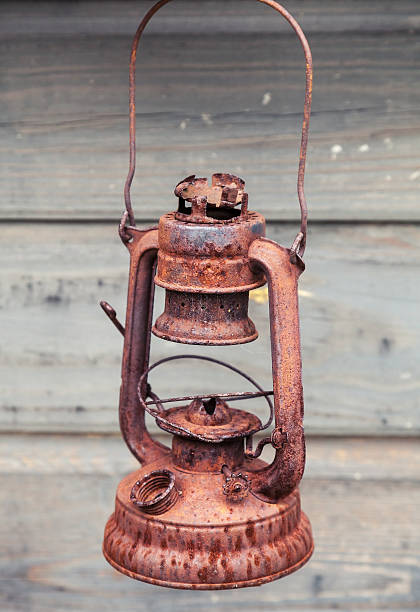 istock Old rusted red kerosene lamp on gray wooden wall 531443025