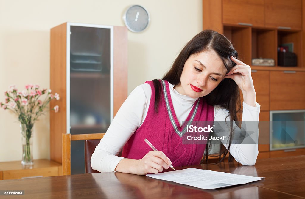 serious brunette woman reading document serious brunette woman reading document at home 20-29 Years Stock Photo