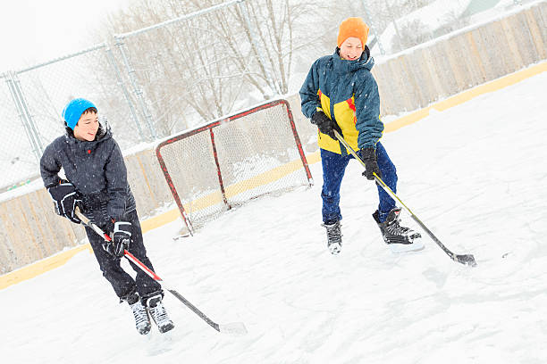 adolescente jugando un partido de hockey al aire libre en una pista de hielo. - ice skating ice hockey child family fotografías e imágenes de stock