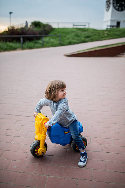 istock Cute kid sitting on toy motorcycle outdoors and looking away. 531460428