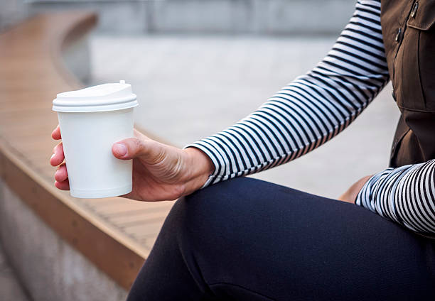 femme mains tenant la tasse de café en papier dans le parc en plein air - mocked photos et images de collection
