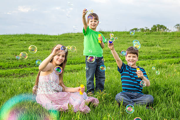 istock Three kids blowing up the soap bubbles on lawn 531463228