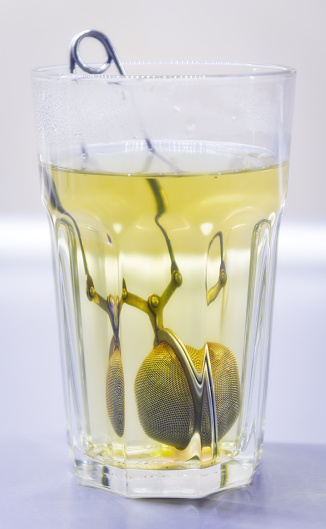 Green tea with tea infuser in a transparent cup. 