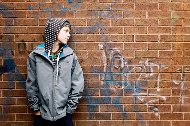 istock Teen Boy Leans Against Brick Wall With Graffiti 531464045
