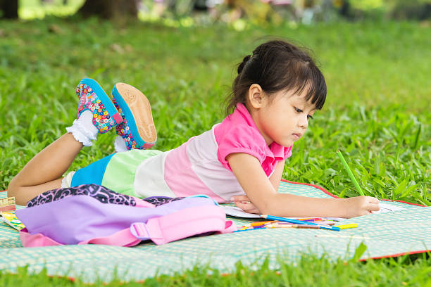istock Young girl outdoors lying on the grass and drawing 531464167