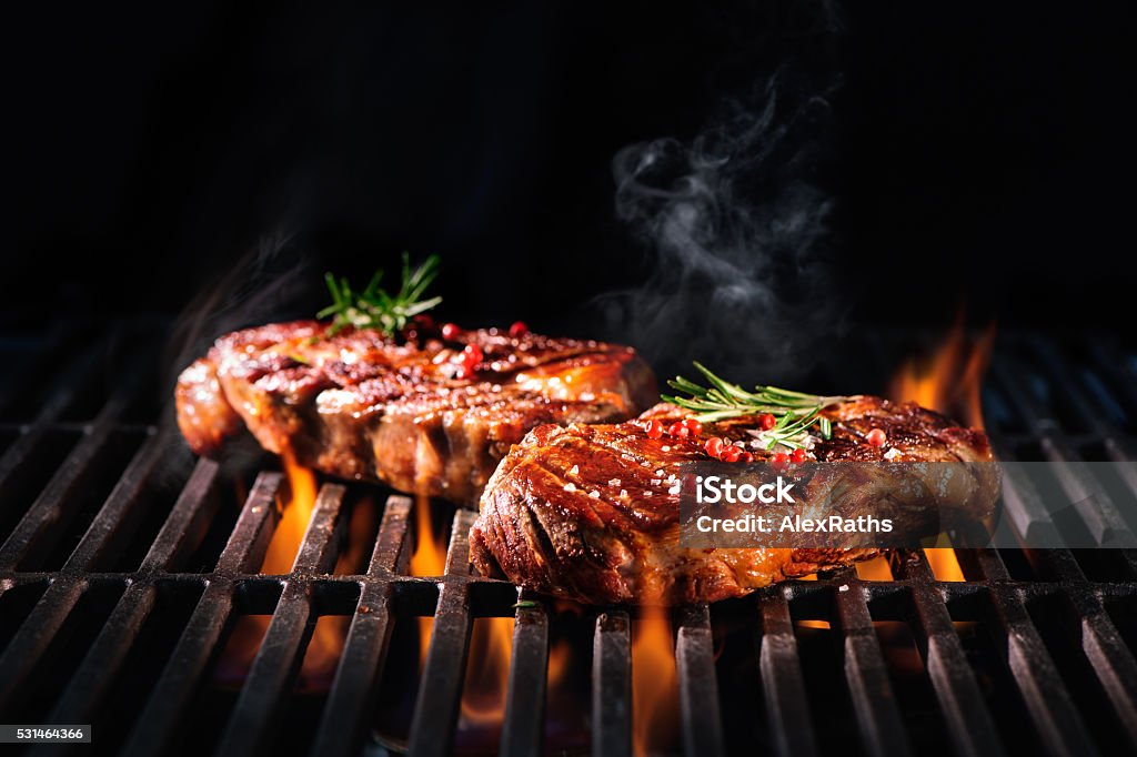 Beef steaks on the grill Beef steaks on the grill with flames Barbecue Grill Stock Photo