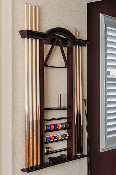 Wall Pool Cue Billiard Stand Pool cue billiard stand mounted to the wall holding cues and pool balls in a residential home. pool cue stock pictures, royalty-free photos & images