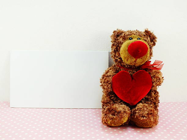 istock cute teddy bear with red heart on pink background 531465774