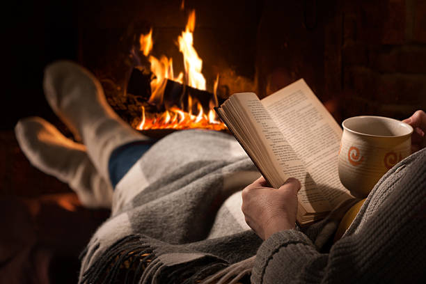 istock Woman reads book near fireplace 531466114