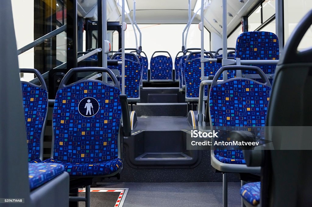 City bus inside Bus inside, city transportation white interior with blue seats in row, retirement places, open doors, handles for standing passengers and bright lights   Bus Stock Photo