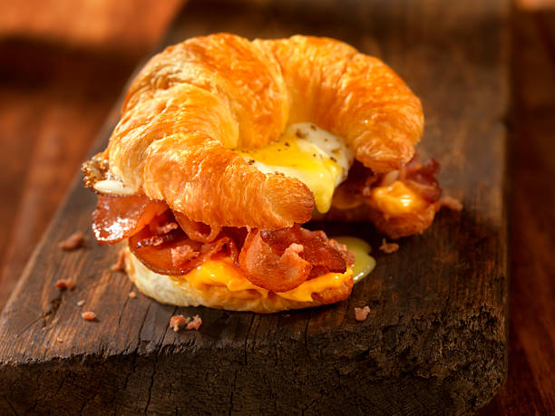 завтрак круассан сэндвич с беконом и яйцом и сыром - sandwich eggs bacon breakfast стоковые фото и изображения
