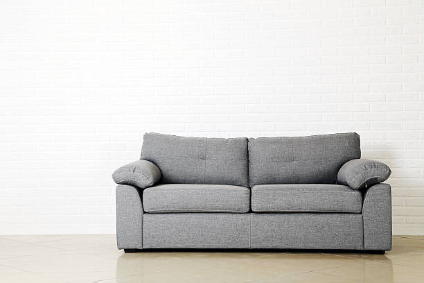 Grey sofa on a white brick wall background stock photo