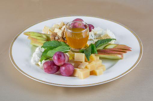 Appetizers. Plate with different kinds of cheese garnished with apples, grape and honey