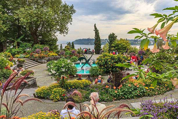 Konstanz, Germany - September 24, 2014: People visit the Mainau Island, in the Lake Constance, famous for its parks and gardens. Every years more than a million of visitors come on the island and stroll among multicolored flowers and butterflies, deciduous and coniferous trees.