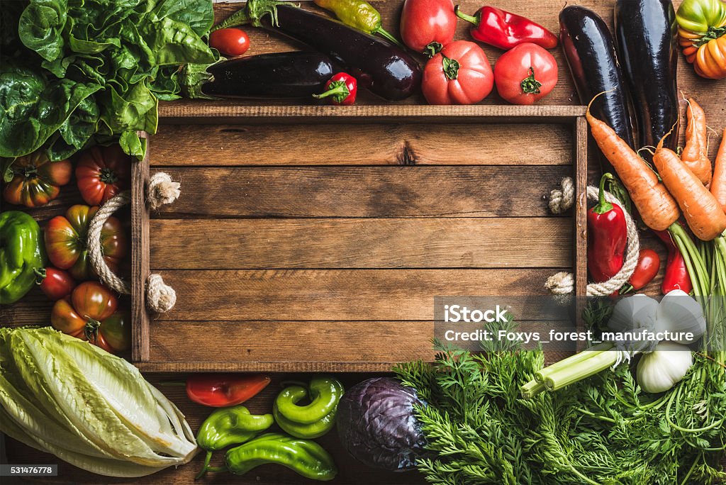 Fresh raw ingredients for healthy cooking or salad making with Fresh raw vegetable ingredients for healthy cooking or salad making with rustic wooden tray in center, top view, copy space. Diet or vegetarian food concept, horizontal composition Food Stock Photo