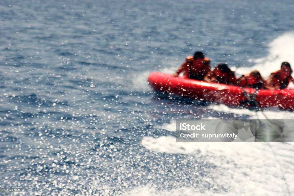 Group of four on tubes on Red sea coast. Group of four bouncing up over wake on tubes on Red sea coast. Eylat. Israel. Inflatable Swim Ring Stock Photo