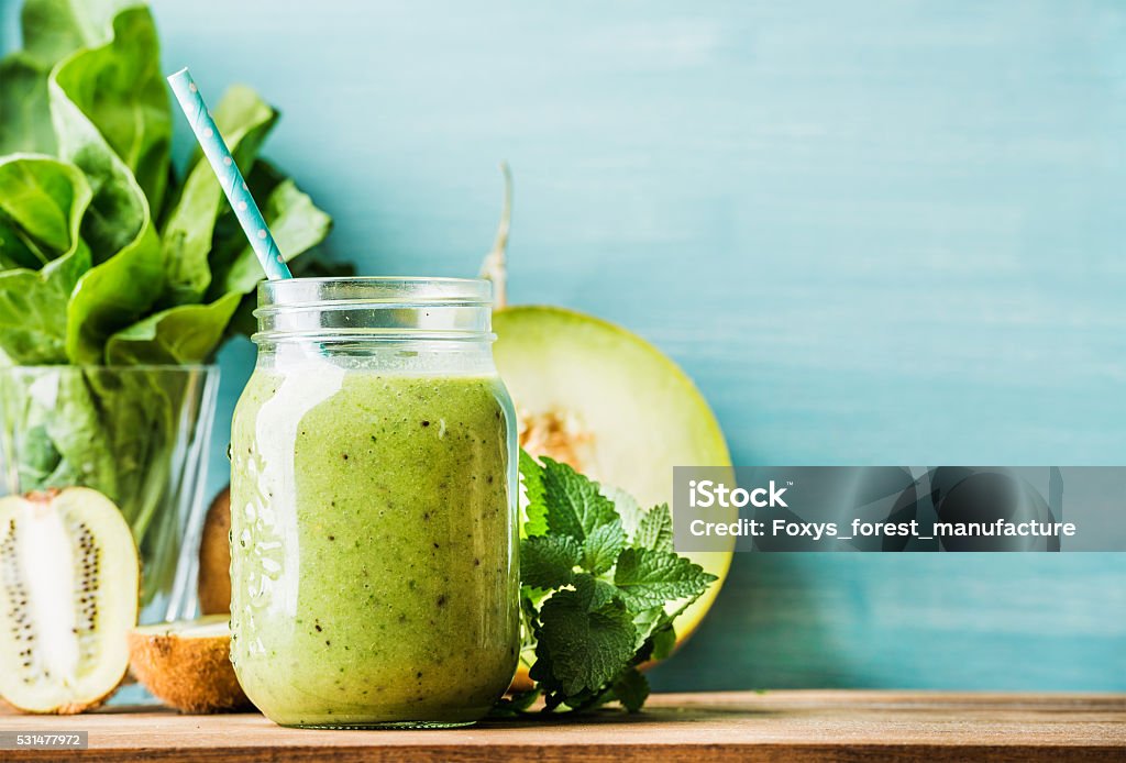Freshly blended green fruit smoothie in glass jar with straw Freshly blended green fruit smoothie in glass jar with straw. Turquoise blue background, copy space Smoothie Stock Photo