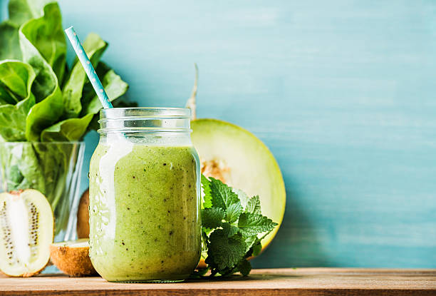 Freshly blended green fruit smoothie in glass jar with straw Freshly blended green fruit smoothie in glass jar with straw. Turquoise blue background, copy space foxys_forest_manufacture stock pictures, royalty-free photos & images