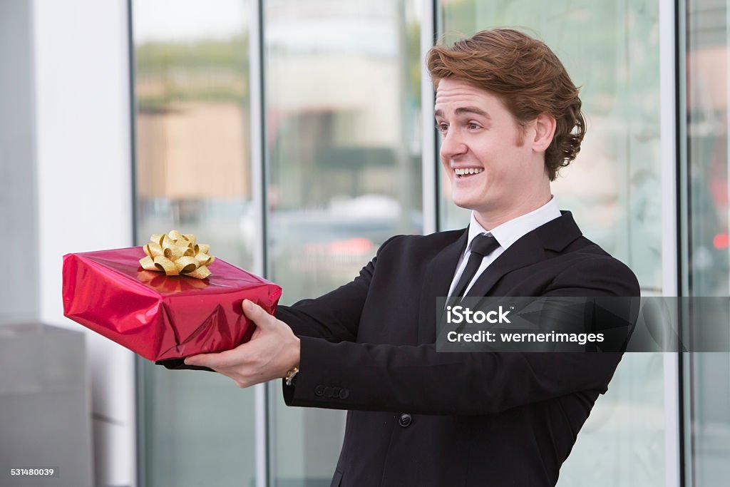 man with gift in his hand man in suit holding a gift in his hands and smiles 2015 Stock Photo