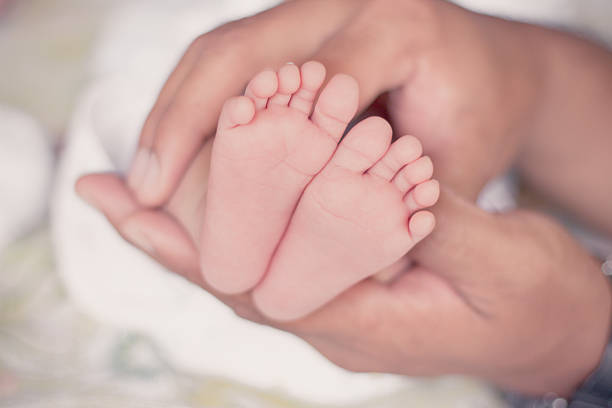 istock Baby feet cupped into father hands 531480139