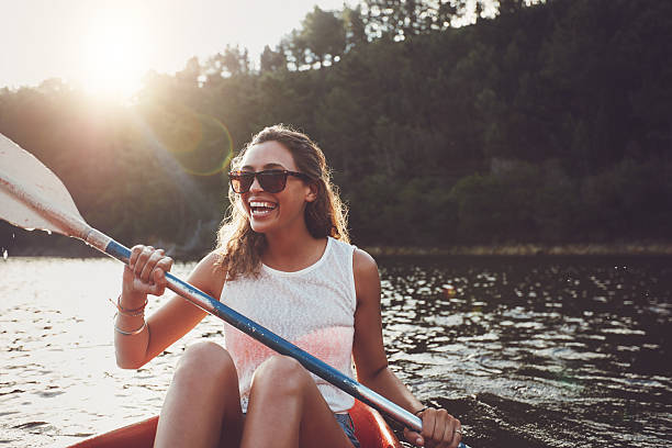 mujer joven sonriente en kayak en un lago - canoeing fotografías e imágenes de stock