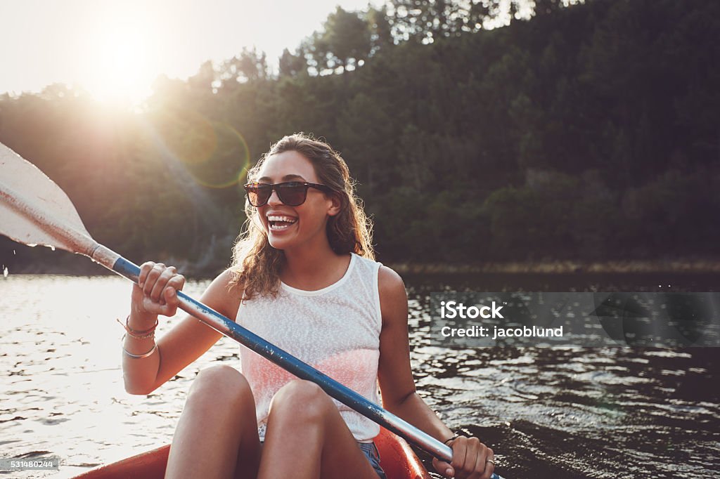 Smiling young woman kayaking on a lake Smiling young woman kayaking on a lake. Happy young woman canoeing in a lake on a summer day. Women Stock Photo