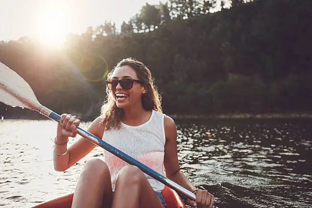 Photo of Smiling young woman kayaking on a lake