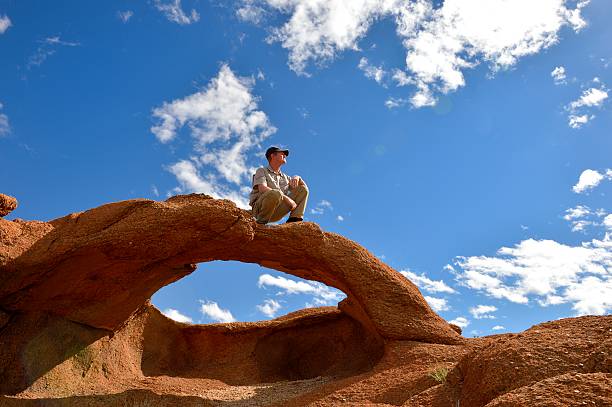 istock Outdoor-type man crouching on desert rock arch landscape 531481243