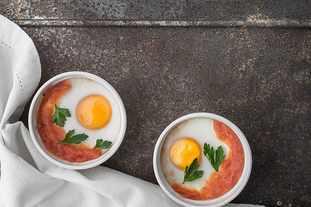 Eggs baked with tomatoes and parsley  on metal background stock photo