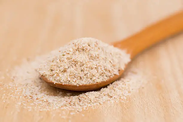 Photo of Wooden Spoon with Psyllium Seeds on wooden background