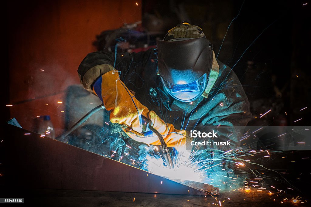 worker welding metal worker welding metal with sparks at factory Welder Stock Photo