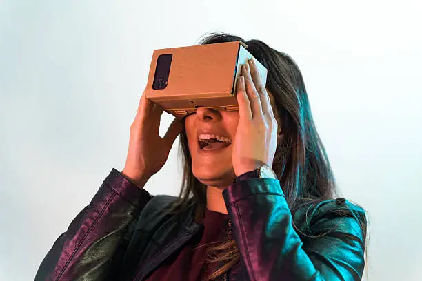 Young smiling girl tries virtual reality cardboard headset . Shot on Canon 5D Mark II