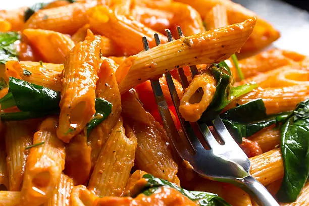 Penne pasta in creamy vodka tomato sauce with sauteed baby spinach leaves