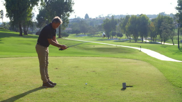 Male Golfer Hitting Tee Shot On Golf Course In Slow Motion
