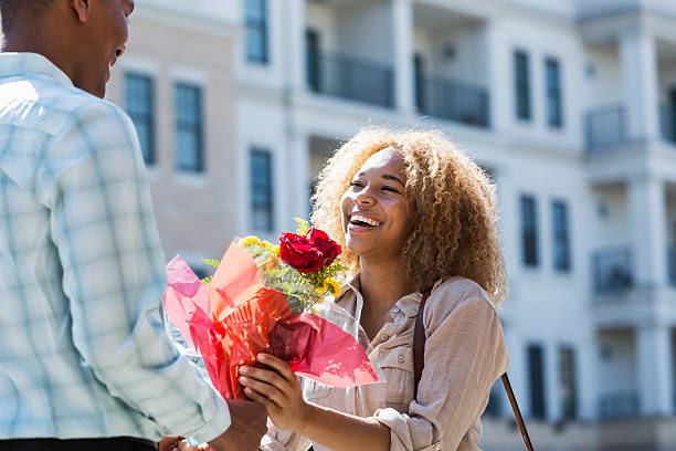 jeune homme donne des fleurs à petite amie - anniversary couple rose black photos et images de collection