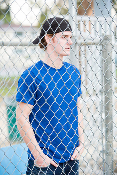 istock young man behind a fence 531505407
