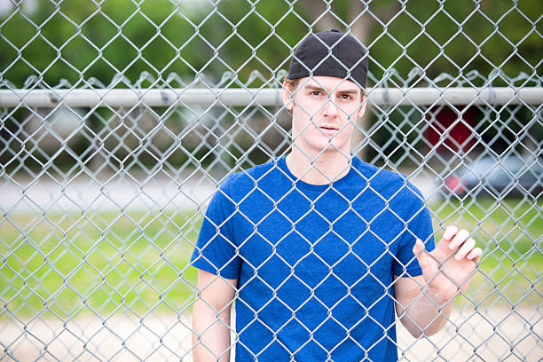 istock young man behind a fence 531505409