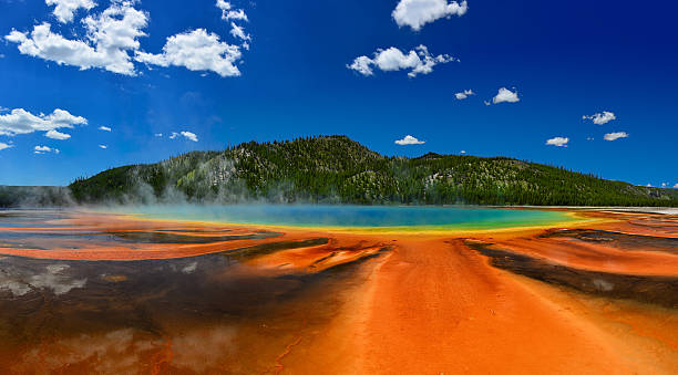 Grand Prismatic Spring in Yellowstone National Park Рanorama of the Grand Prismatic Spring in Yellowstone National Park WY USA. In the background are visible the mountains covered with forests. midway geyser basin photos stock pictures, royalty-free photos & images