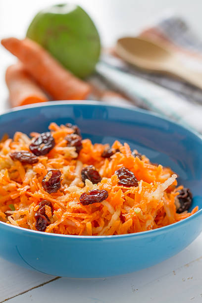 Salad - carrot, apple and raisins in blue bowl