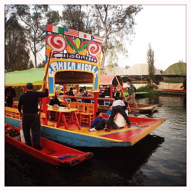 Trajinera boats in Xochimilco, Mexico City Xochimilco, Mexico City, Mexico - December 30, 2014: Guests enjoying the ride on a trainer boat, steered by a gondolieri with a pole. trajinera stock pictures, royalty-free photos & images